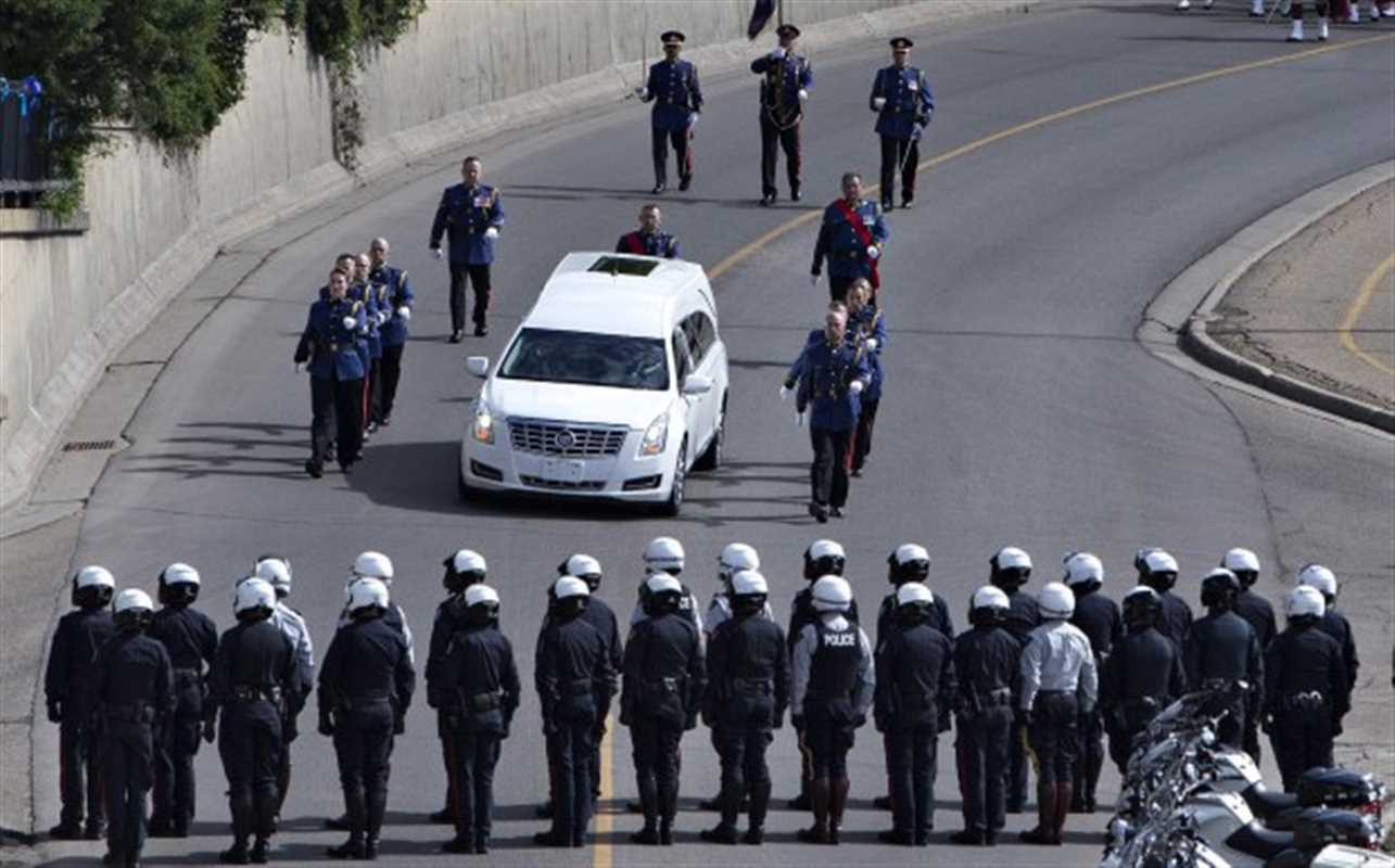 Police stand at attention during the funeral procession for slain police officer Const. Daniel Woodall, in Edmonton, Alta., on Wednesday, June 17, 2015. THE CANADIAN PRESS/Jason Franson