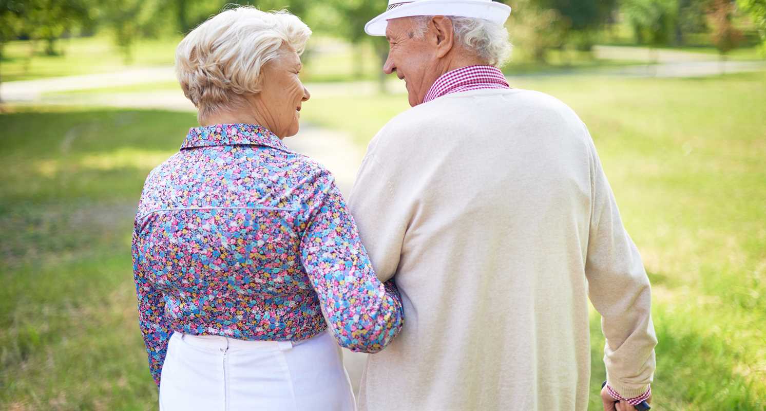 Back view of happy senior couple talking while taking a walk in the park